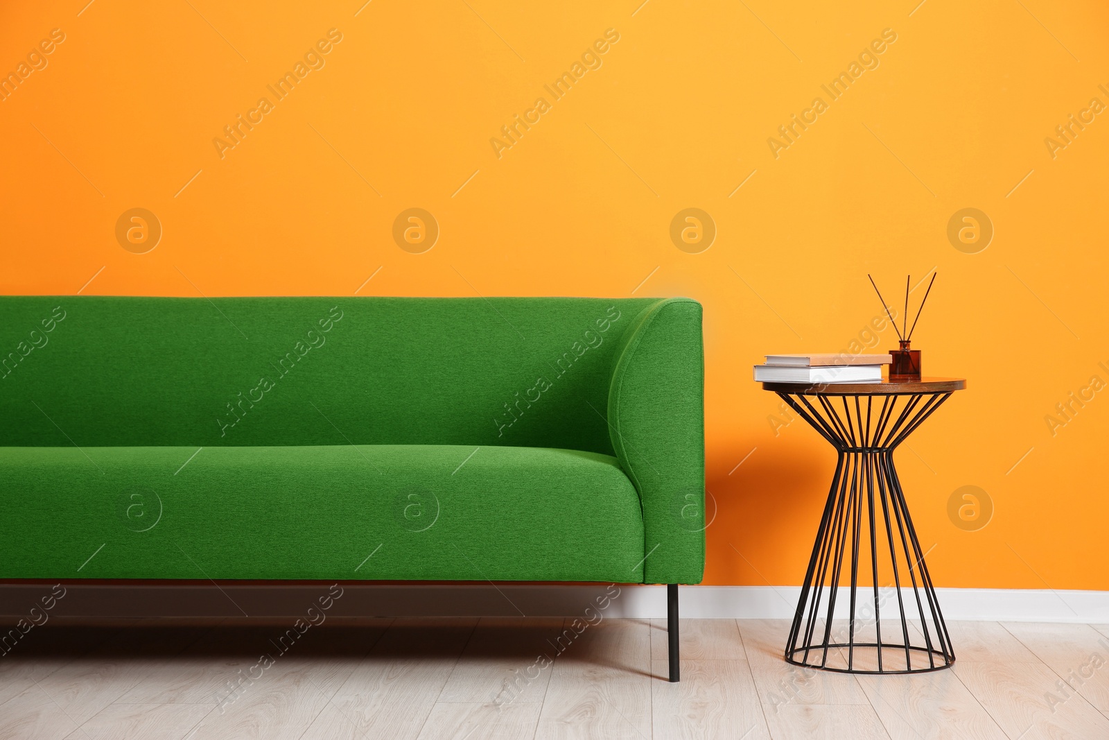 Image of Comfortable green sofa and table near orange wall in room