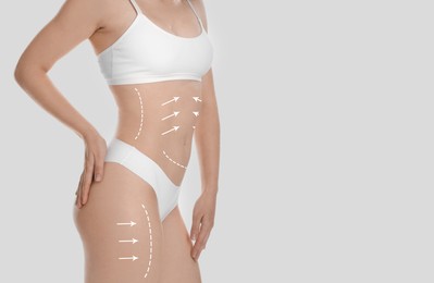 Woman with perfect slim body on light grey background, closeup. Figure correction arrows and lines on skin