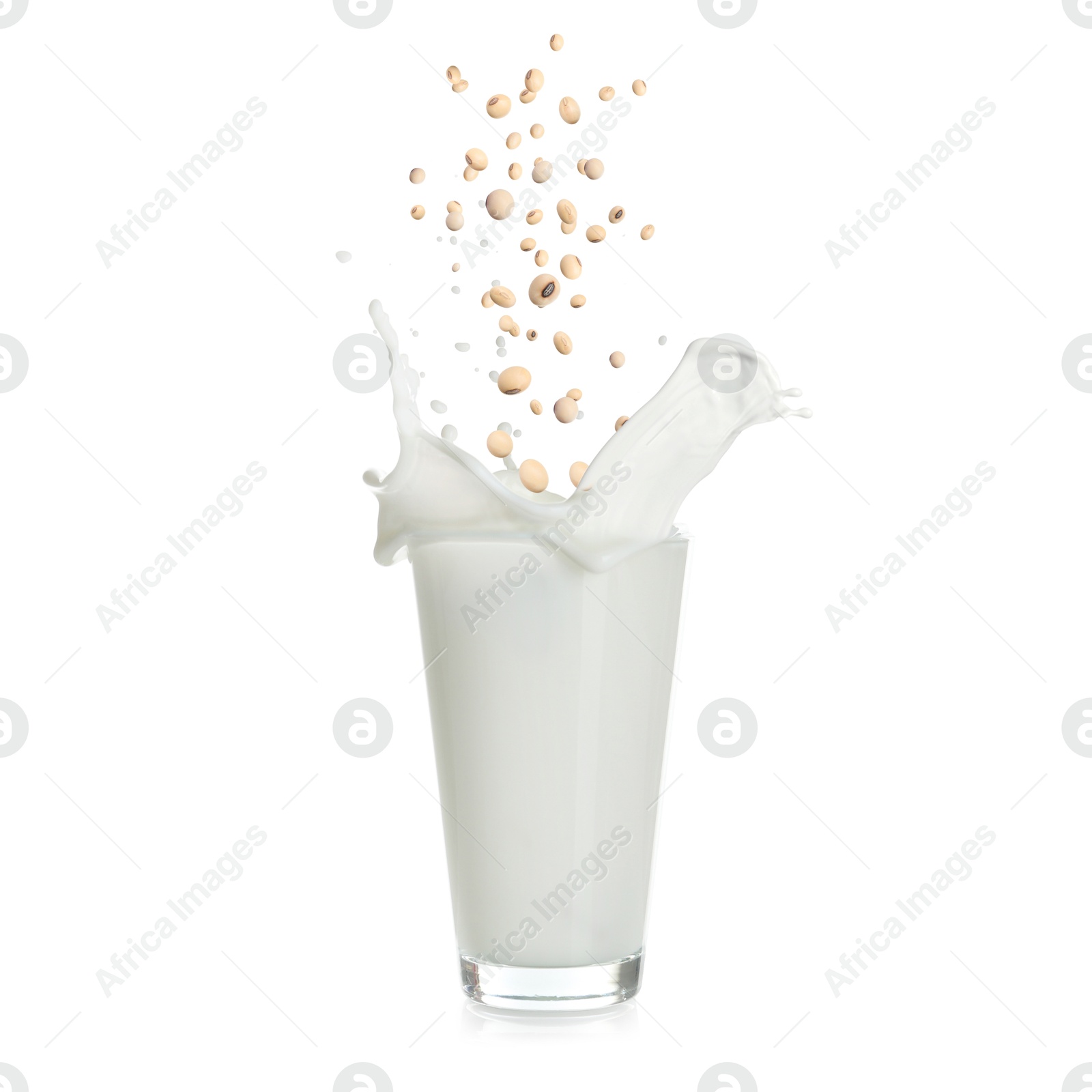 Image of Soy beans falling into glass of plant milk on white background