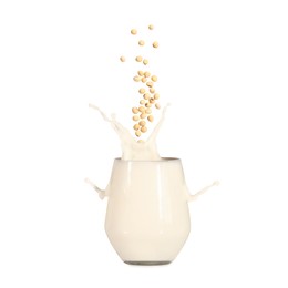 Image of Soy beans falling into glass of plant milk on white background