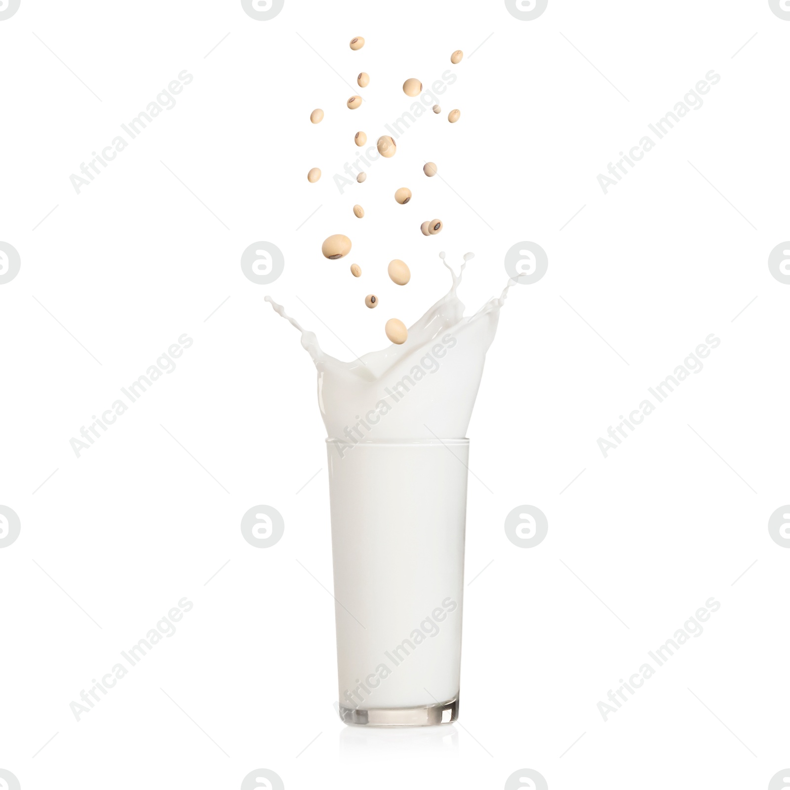 Image of Soy beans falling into glass of plant milk on white background