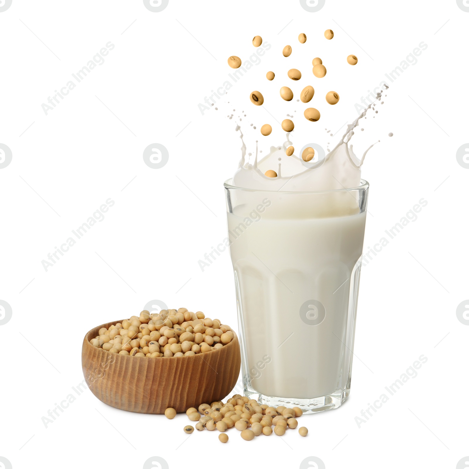 Image of Soy beans falling into glass of plant milk on white background