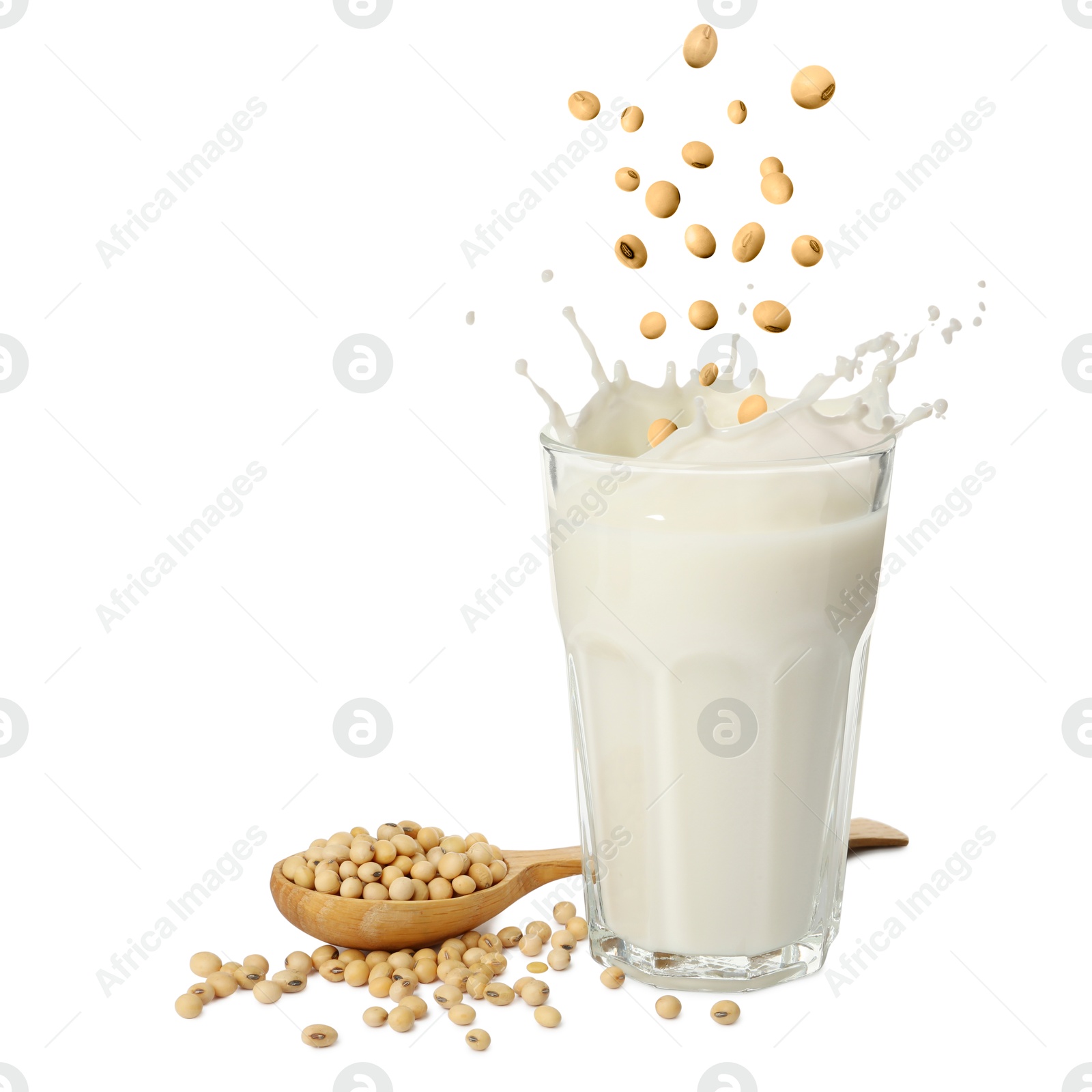 Image of Soy beans falling into glass of plant milk on white background