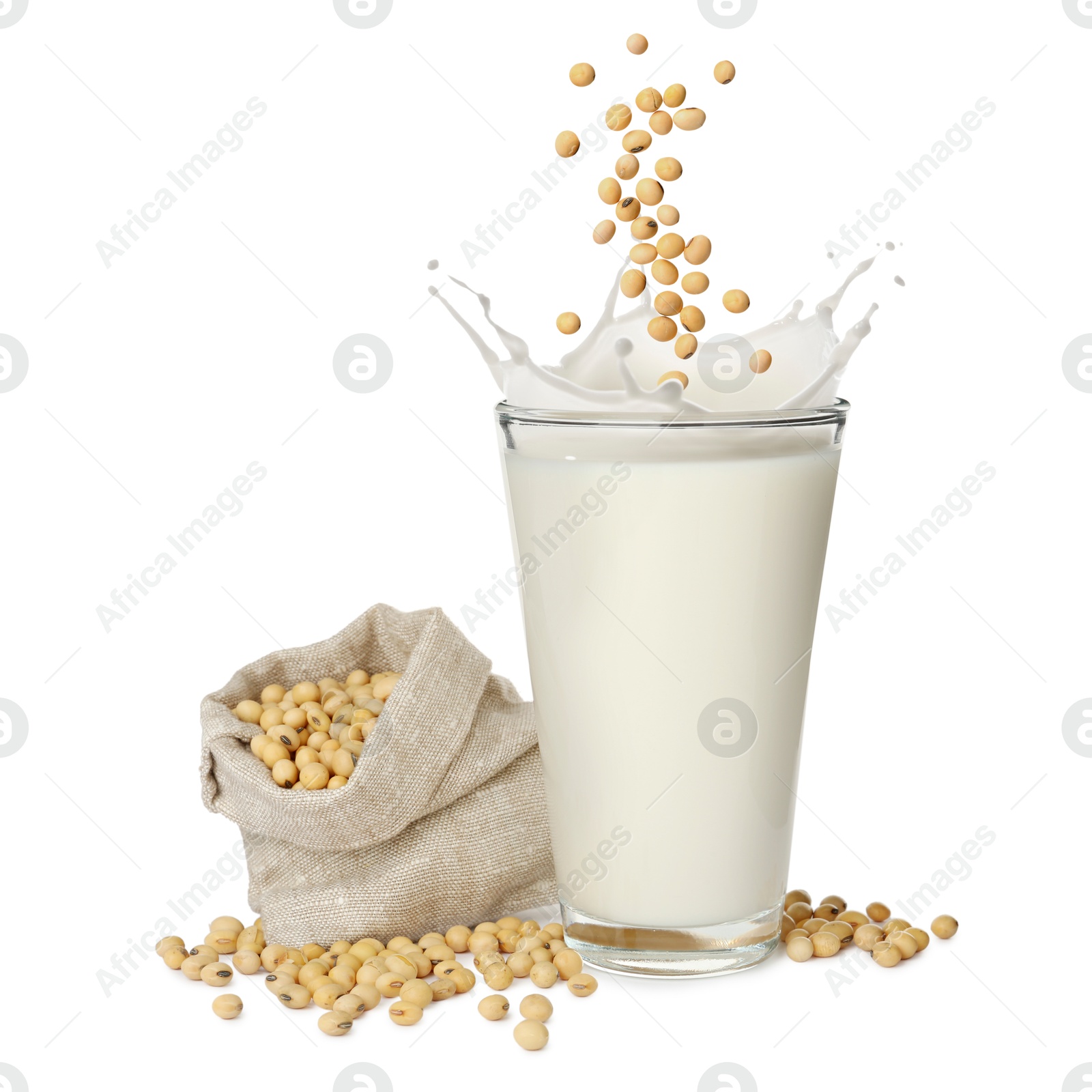 Image of Soy beans falling into glass of plant milk on white background