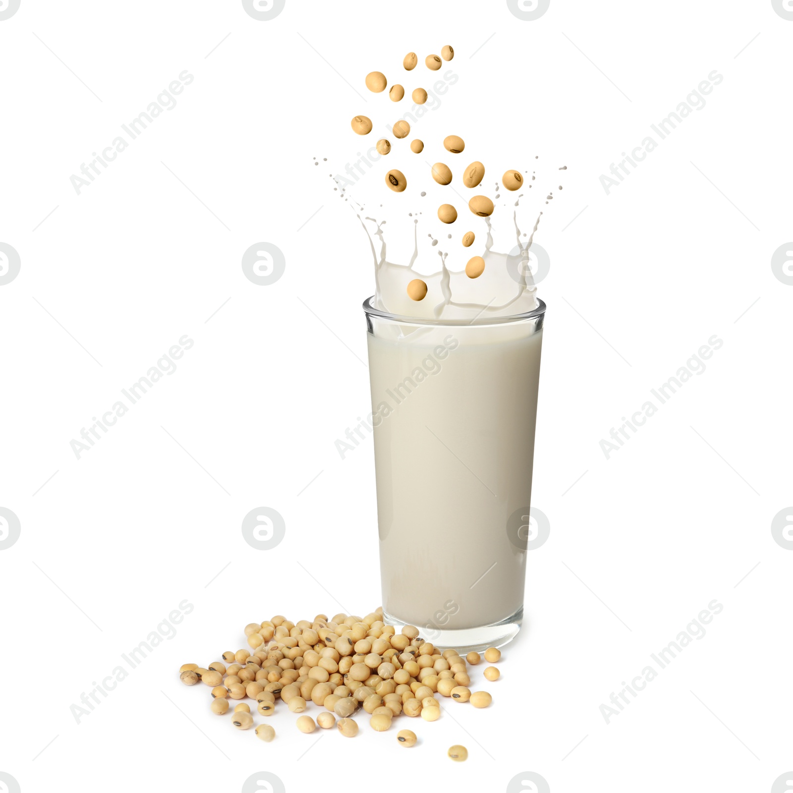 Image of Soy beans falling into glass of plant milk on white background