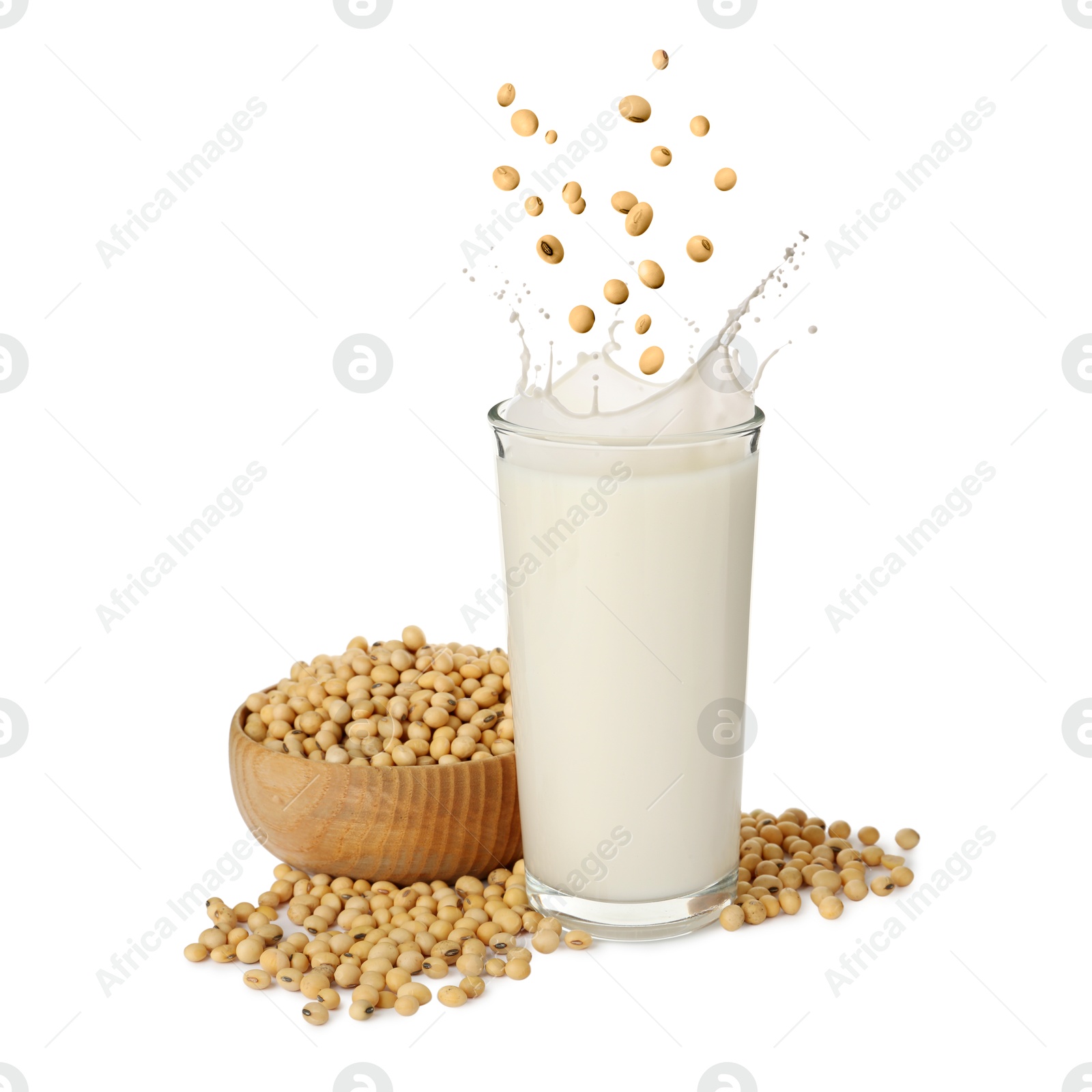 Image of Soy beans falling into glass of plant milk on white background