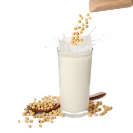 Image of Soy beans falling from wooden scoop into glass of plant milk on white background