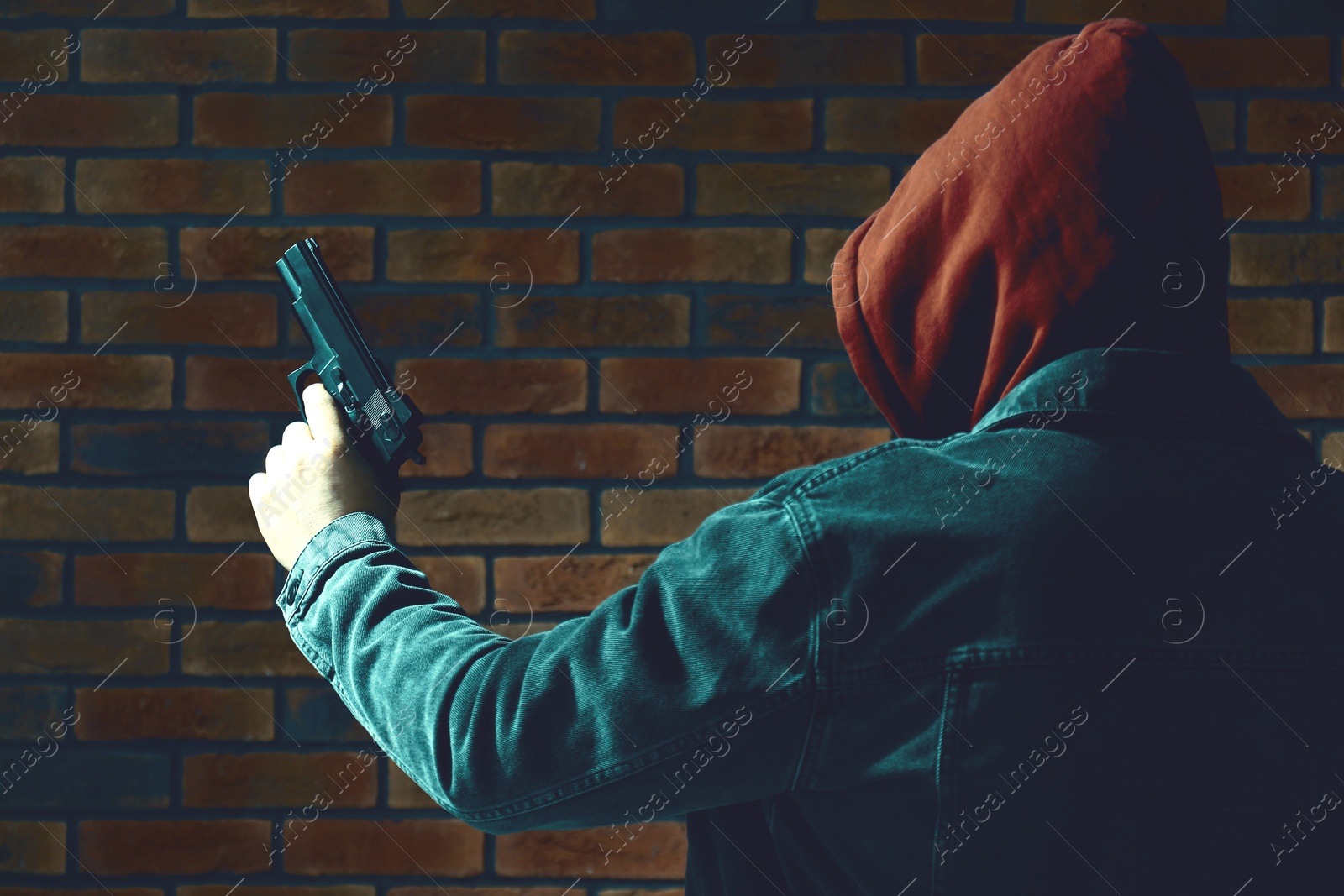 Image of Dangerous criminal with gun near brick wall, back view. Armed robbery