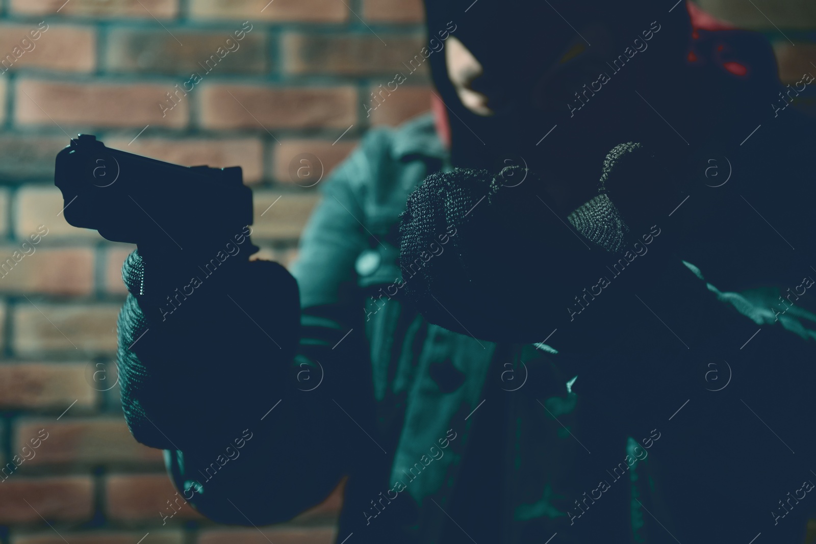 Image of Dangerous criminal with gun near brick wall, selective focus. Armed robbery