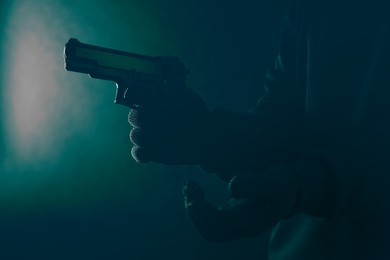 Image of Dangerous criminal with gun on black background, closeup. Armed robbery