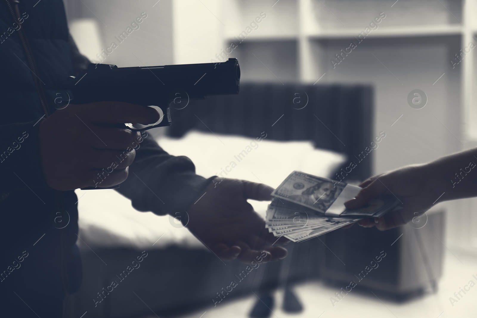 Image of Woman giving money to criminal with gun indoors, closeup. Armed robbery