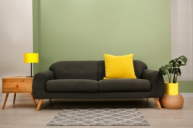 Image of Comfortable sofa and side table near light green wall in room