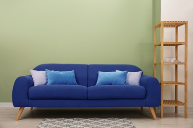 Image of Comfortable blue sofa and shelving unit near light green wall in room