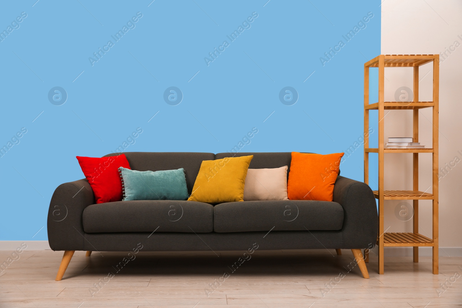 Image of Comfortable grey sofa and shelving unit near light blue wall in room