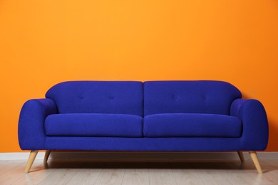 Image of Comfortable blue sofa near orange wall in room