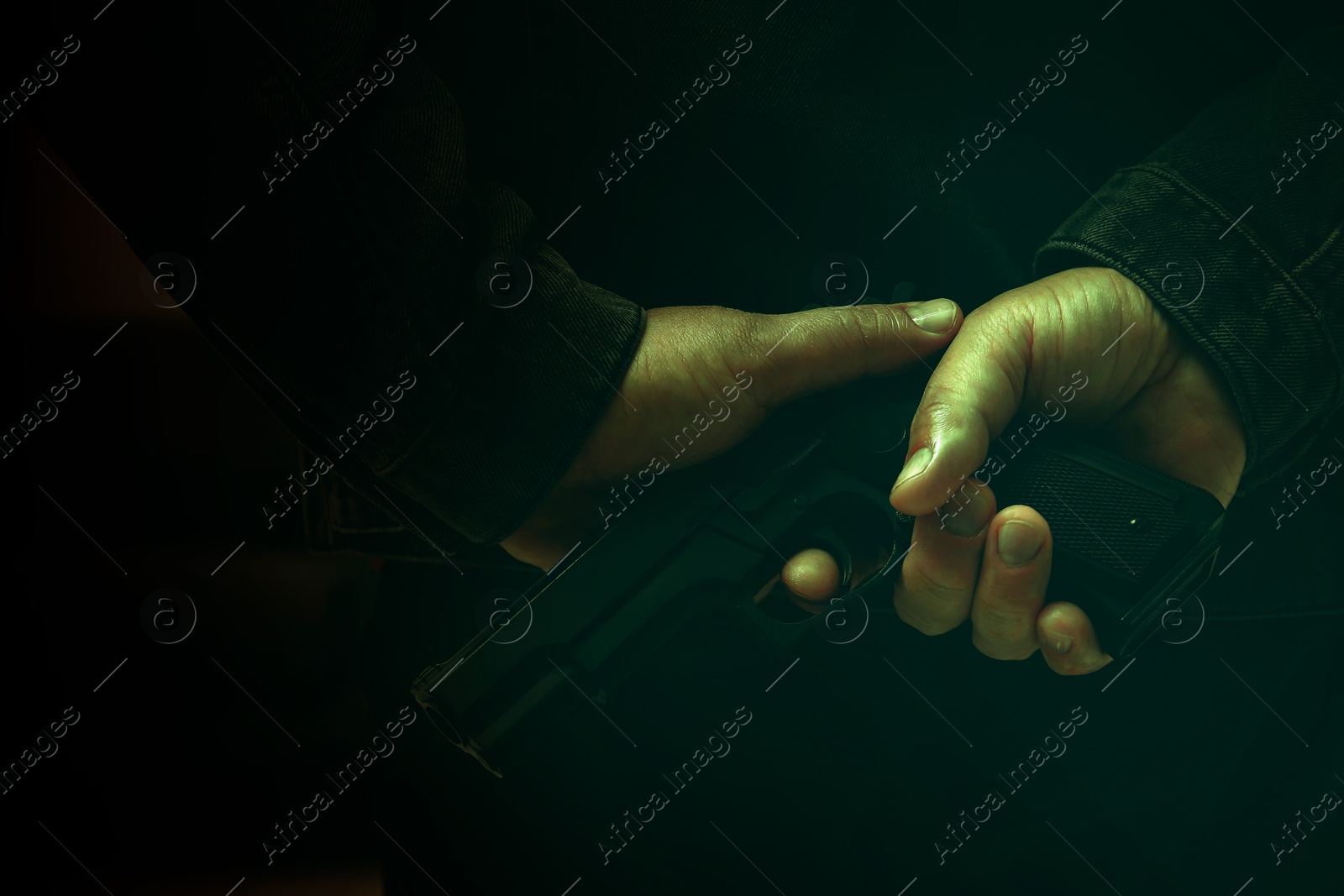 Image of Man hiding gun behind his back in darkness, closeup. Armed robbery