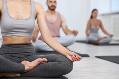 Group of people meditating on mats in yoga class, closeup