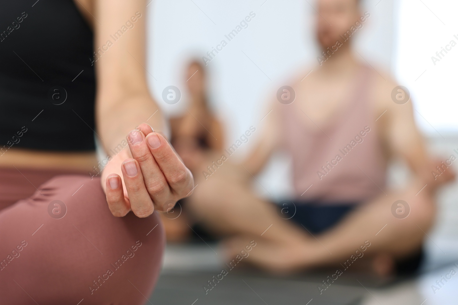 Photo of Group of people meditating on mats in yoga class, closeup