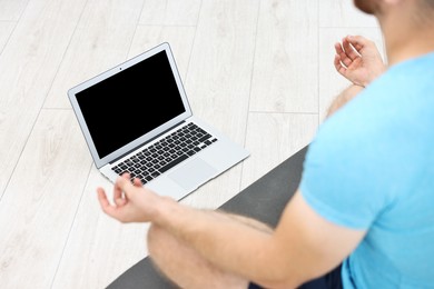 Photo of Man meditating near laptop at home, closeup