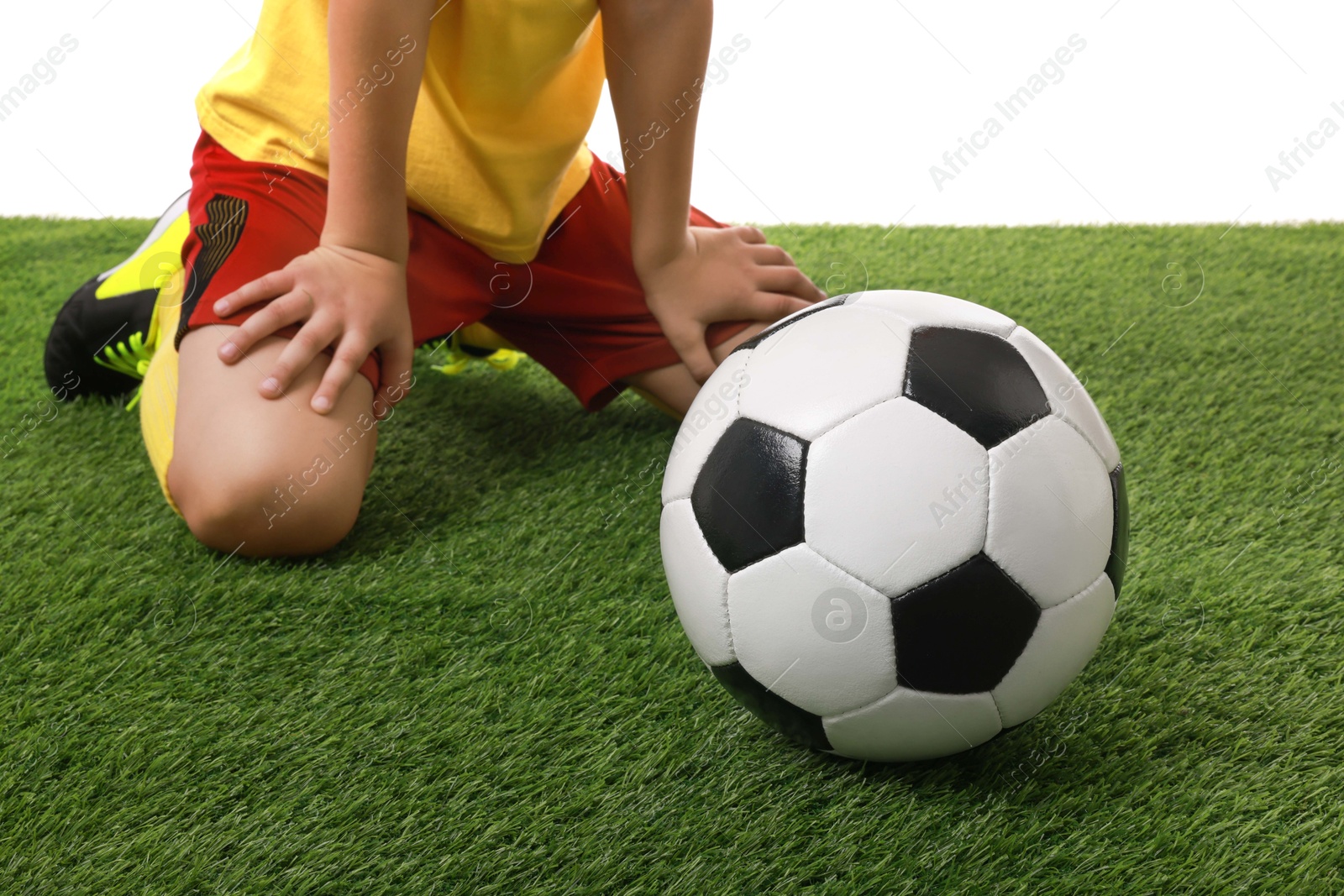 Photo of Football player with soccer ball on artificial grass against white background, closeup