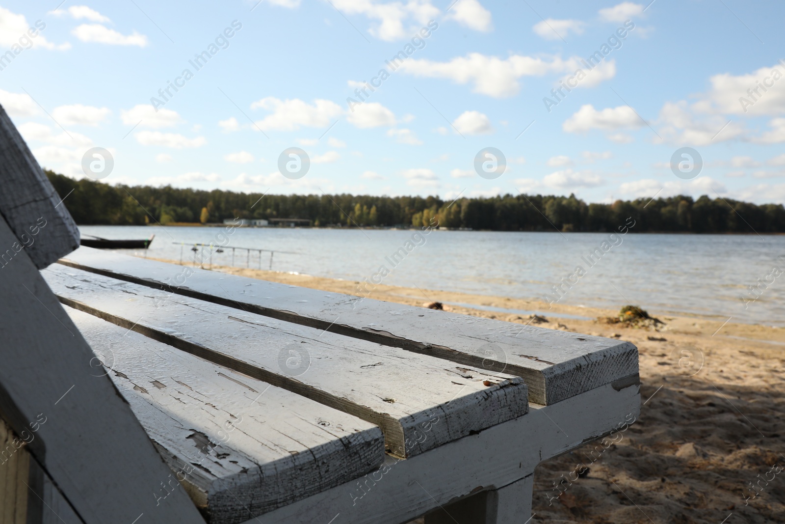 Photo of Wooden bench near river on sunny day, closeup