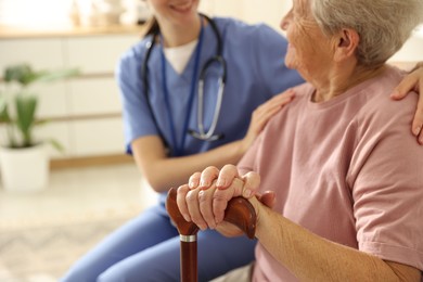 Photo of Caregiver supporting senior woman indoors, closeup. Home health care service