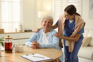 Caregiver supporting senior woman indoors. Home health care service