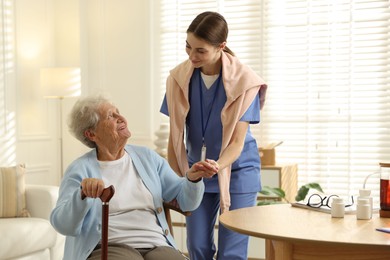 Caregiver supporting senior woman indoors. Home health care service