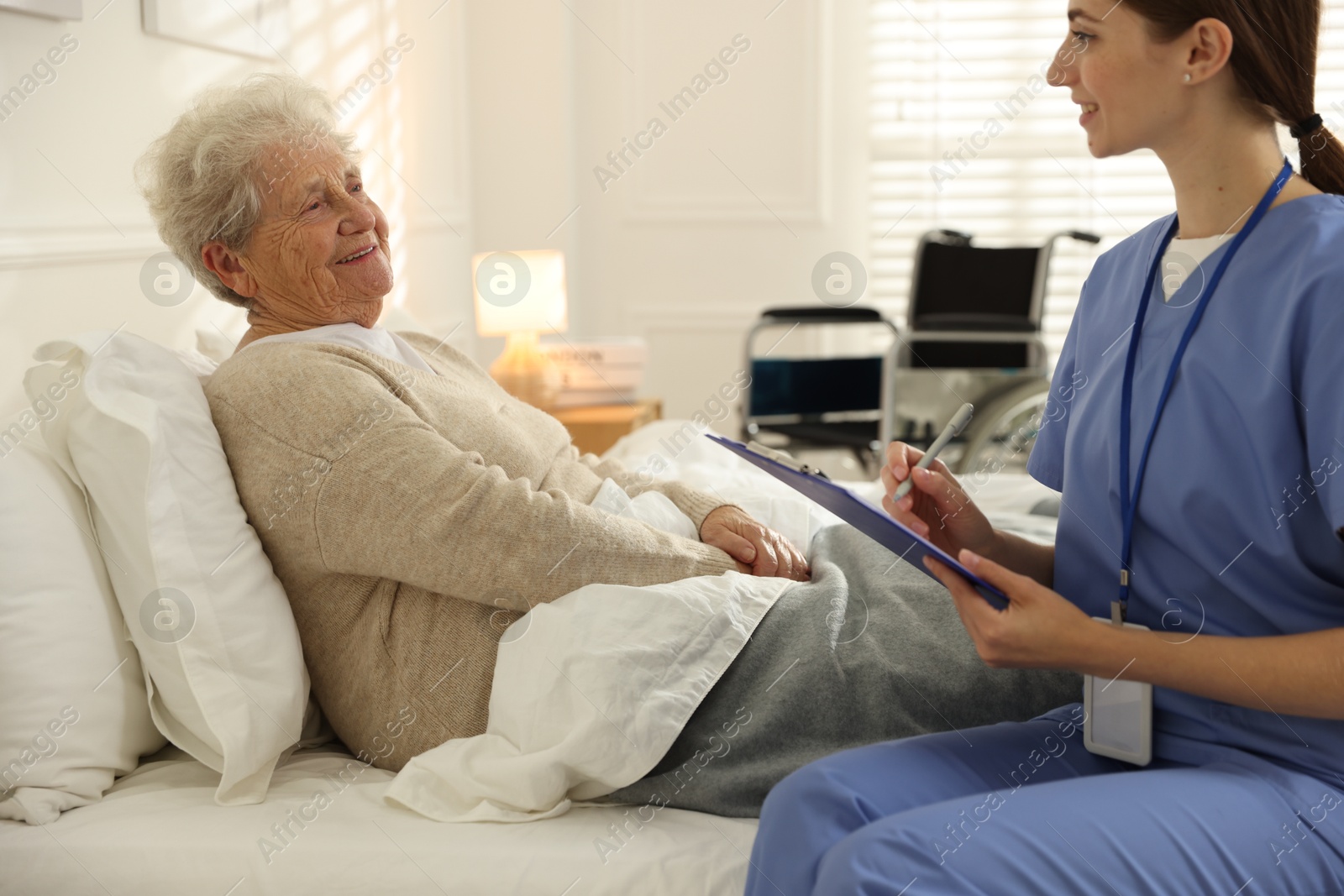 Photo of Caregiver examining senior woman on bed indoors. Home health care service