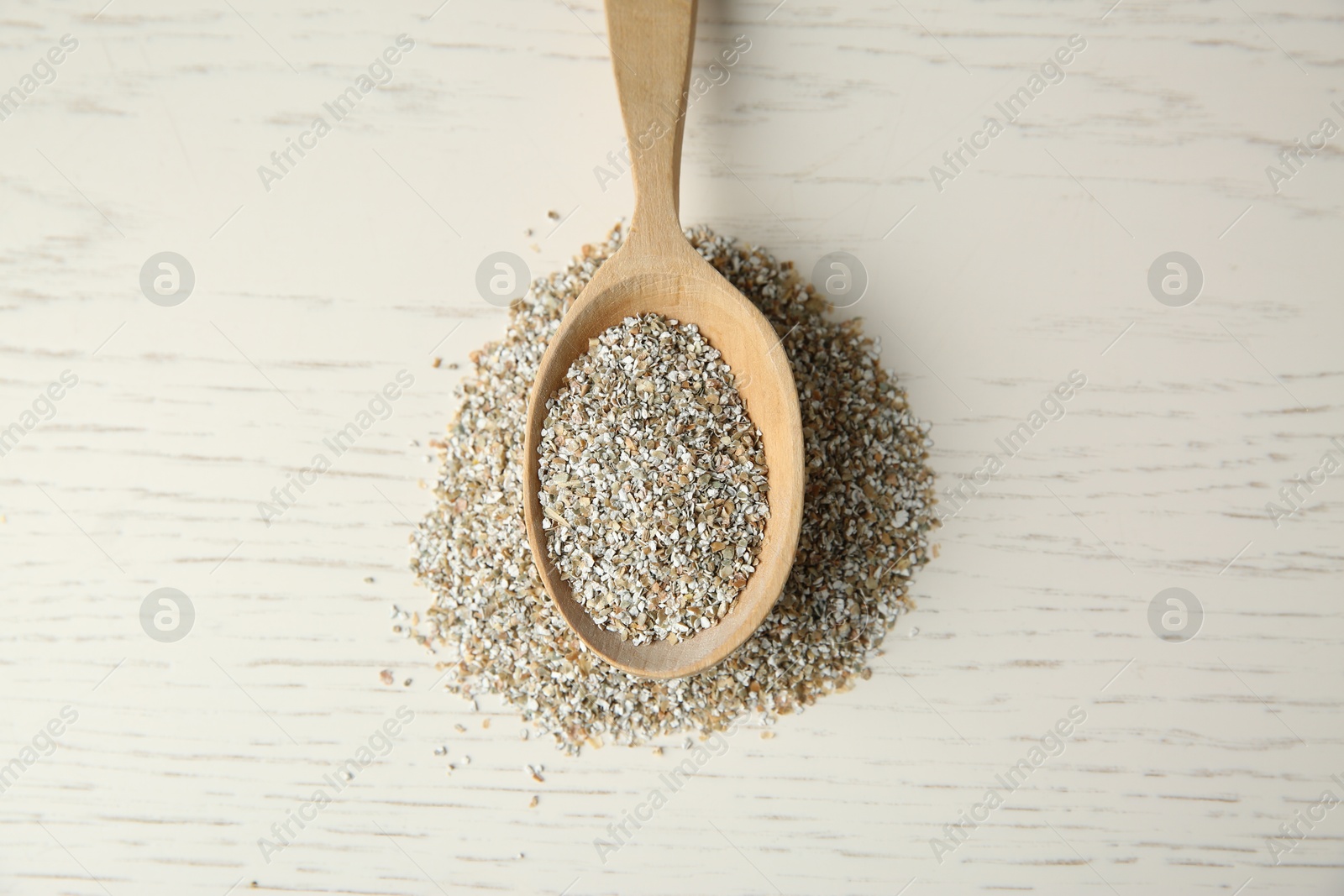 Photo of Pile of fresh rye bran and spoon on light wooden table, top view