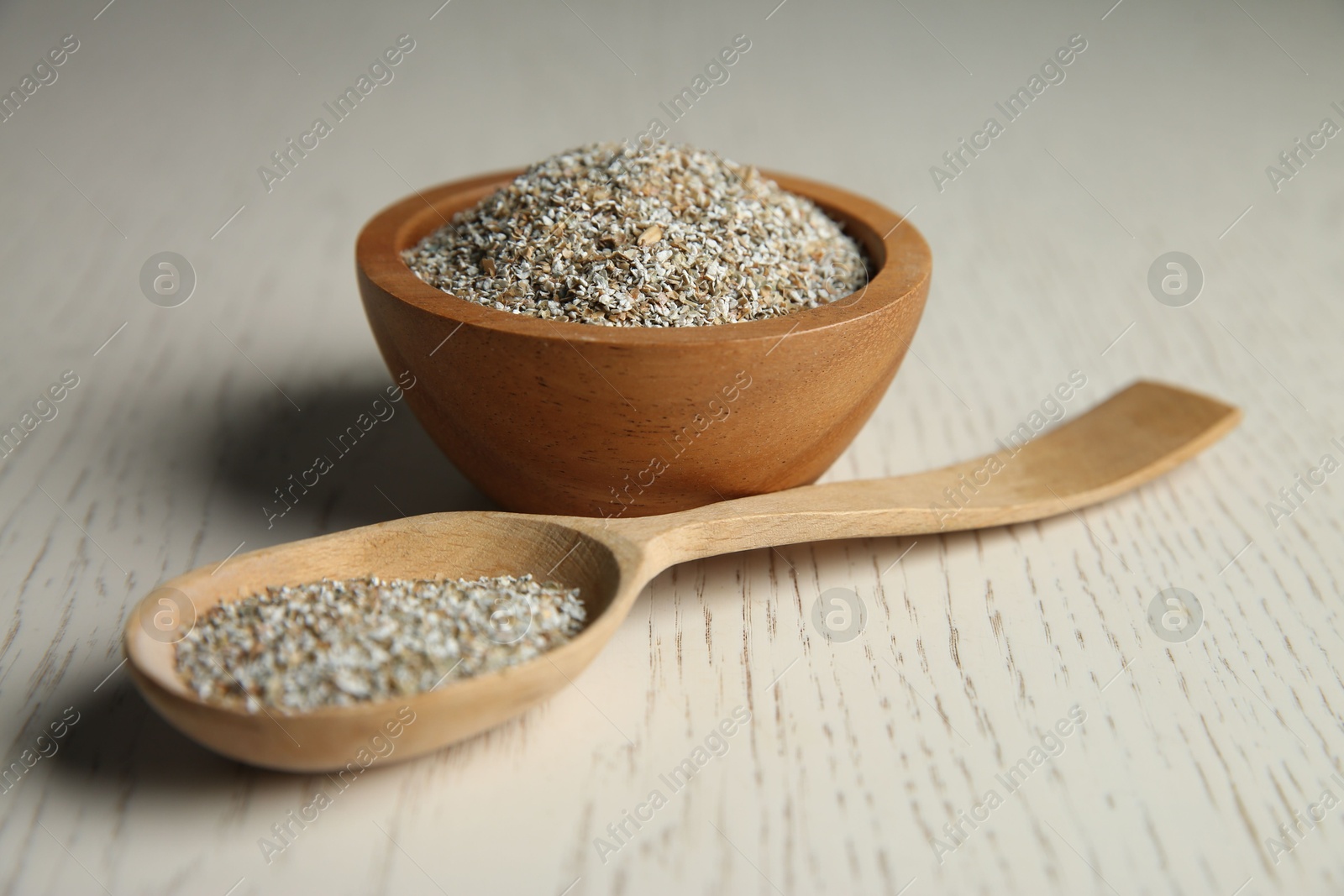 Photo of Fresh rye bran in bowl and spoon on light wooden table, closeup