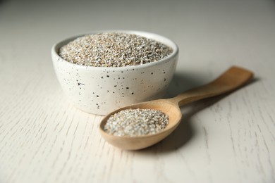 Photo of Fresh rye bran in bowl and spoon on light wooden table, closeup