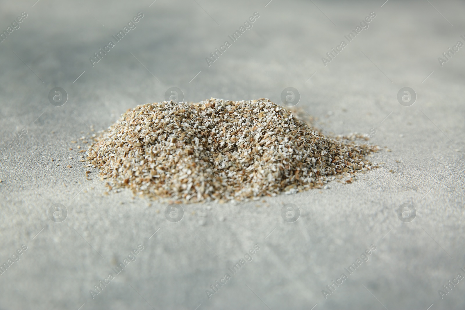 Photo of Pile of fresh rye bran on grey textured table, closeup