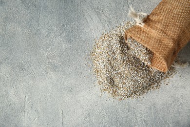 Photo of Sack with fresh rye bran on grey textured table, top view. Space for text