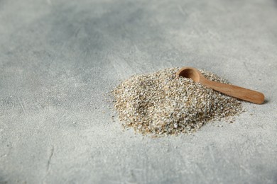 Photo of Pile of fresh rye bran and spoon on grey textured table. Space for text