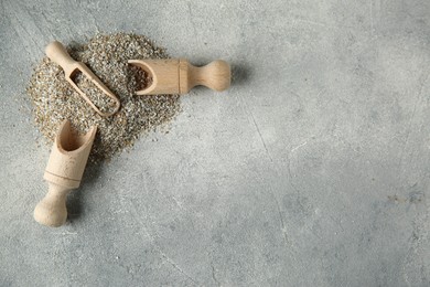 Photo of Pile of fresh rye bran and scoops on grey textured table, top view. Space for text