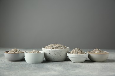 Photo of Fresh rye bran in bowls on grey textured table. Space for text