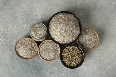 Photo of Fresh rye bran and kernels on grey textured table, flat lay