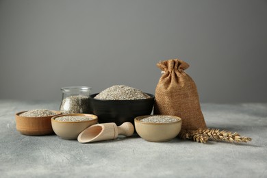 Photo of Fresh rye bran, scoop and spikelets on grey textured table