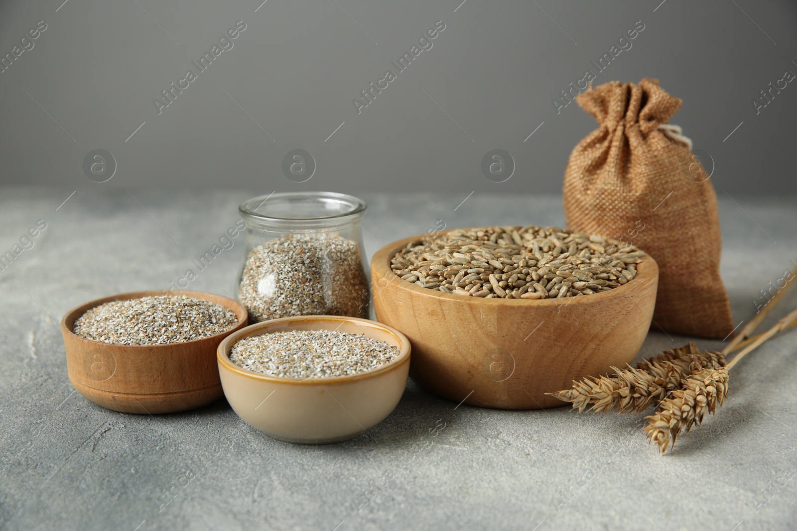 Photo of Fresh rye bran, kernels and spikelets on grey textured table