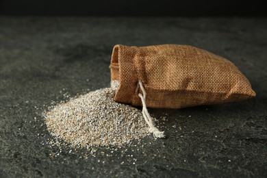 Photo of Sack with fresh rye bran on grey textured table, closeup