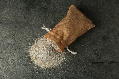 Photo of Sack with fresh rye bran on grey textured table, top view