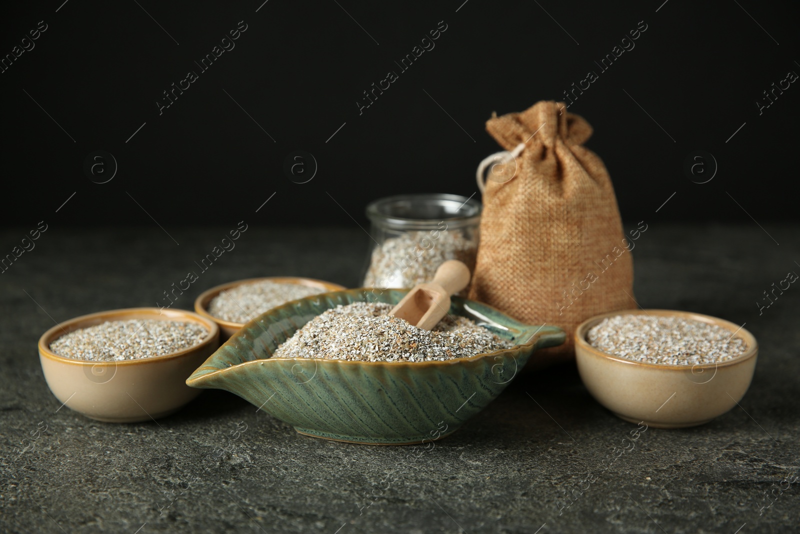 Photo of Fresh rye bran and scoop on grey textured table