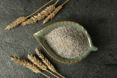 Photo of Fresh rye bran and spikelets on grey textured table, flat lay