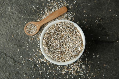 Photo of Fresh rye bran and spoon on grey textured table, flat lay