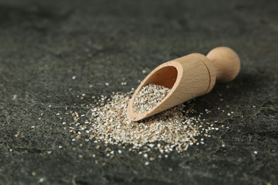 Photo of Fresh rye bran and scoop on grey textured table, closeup