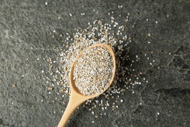 Photo of Fresh rye bran and spoon on grey textured table, top view