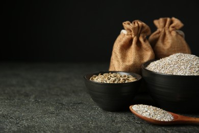 Photo of Fresh rye bran, kernels and spoon on grey textured table, closeup. Space for text