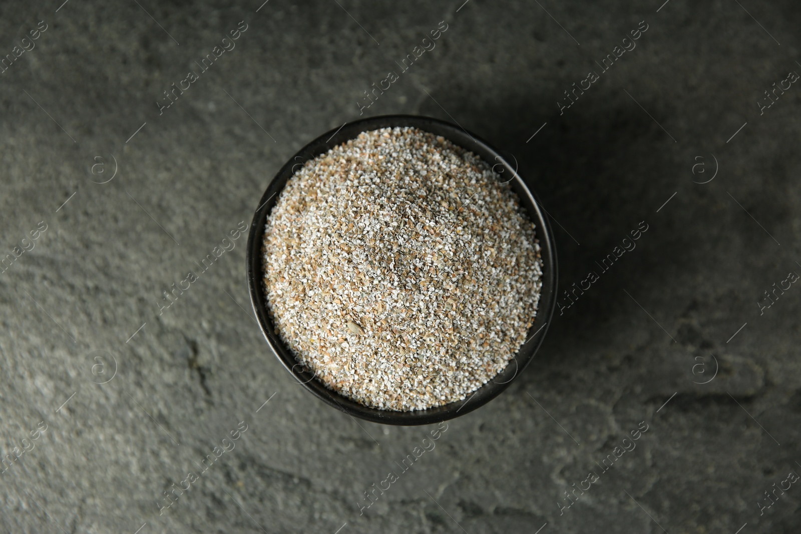 Photo of Fresh rye bran in bowl on grey textured table, top view