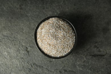 Photo of Fresh rye bran in bowl on grey textured table, top view